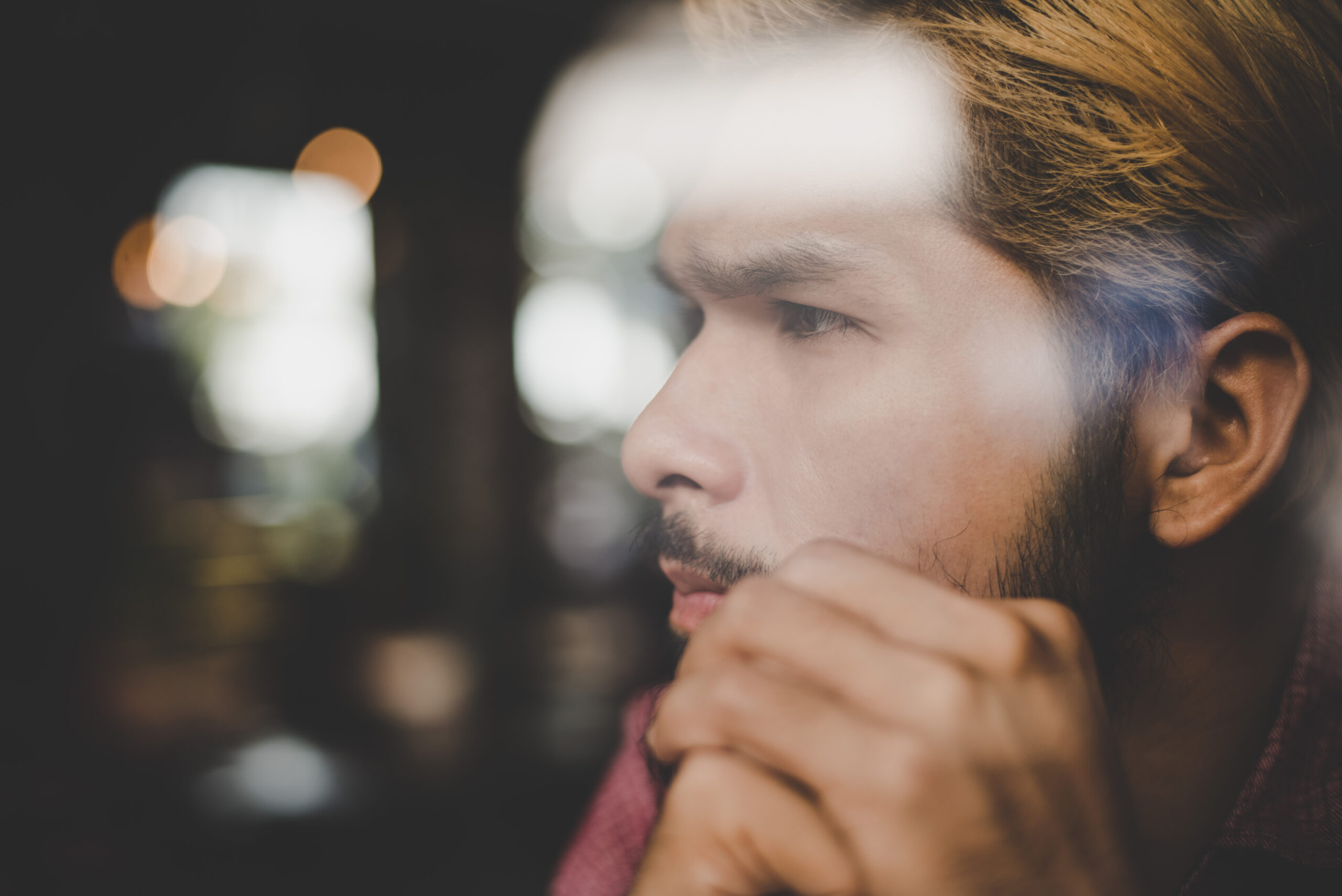 Reflective young man sitting in a café window contemplating the connection between mental and physical health